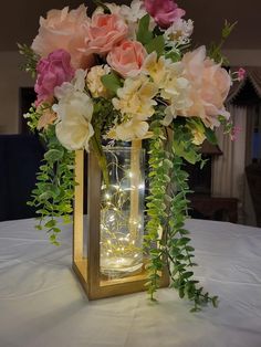 a vase filled with lots of flowers on top of a white tablecloth covered table