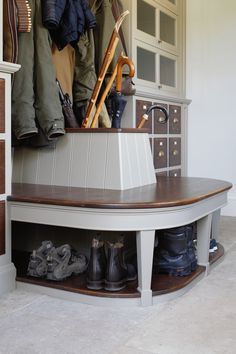 a coat rack with shoes and umbrellas on it next to a closet full of coats