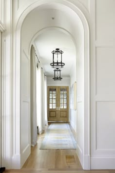 an archway leading to the front door of a house with wood floors and white walls