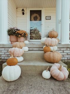 pumpkins and gourds sitting on the front steps of a house