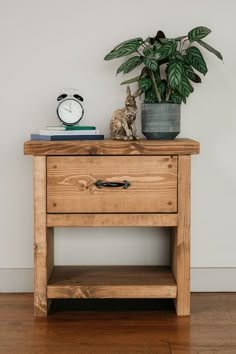 a small wooden table with a clock and plant on top