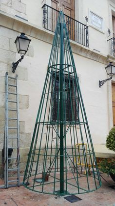 a green metal structure sitting in front of a building