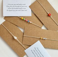 three cards with string and bead on them, one has a note attached to it