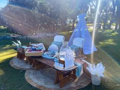 a picnic table set up in the middle of a field with chairs and plates on it