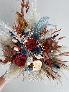 a bridal bouquet with red, white and blue flowers is held by someone's hand