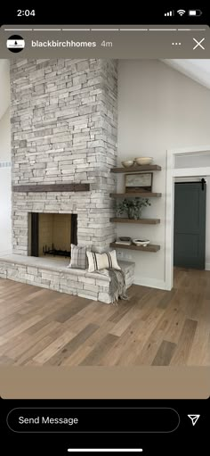 a living room with a stone fireplace and wooden floors