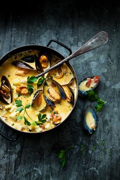 a pan filled with mussels and sauce on top of a table