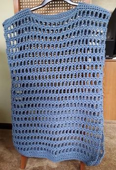 a blue crocheted blanket sitting on top of a wooden chair