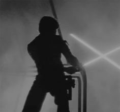 a man standing on top of a metal structure holding a light saber in his hand