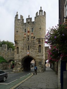 an old stone castle with a car parked on the side walk in front of it