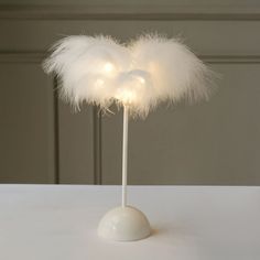 a white table topped with a light up feather decoration on top of a wooden stick