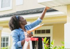 a woman is painting the side of a house