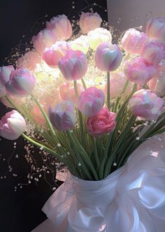 a bouquet of pink and white tulips in a vase on a black background