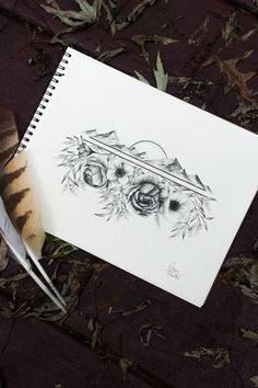 a pen and ink drawing on top of a piece of paper next to a feather