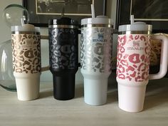 four travel mugs are lined up next to each other on a table in front of a framed photograph