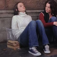 two women sitting on the ground next to each other