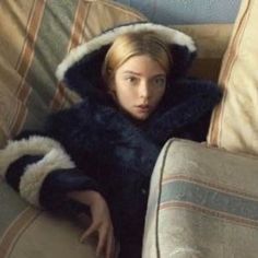 a woman in a fur coat sitting on a couch with her head under the covers