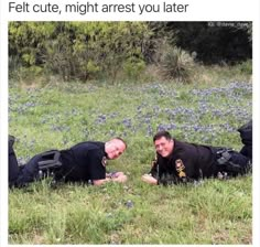 two police officers laying in the grass with their arms around each other and smiling at the camera