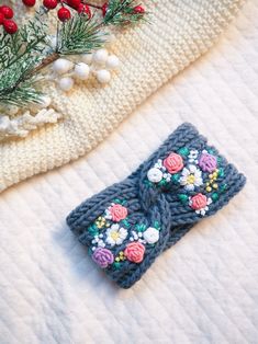 a crocheted bow with flowers is laying on a white blanket next to berries