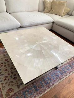 a large white couch sitting next to a table on top of a rug in a living room