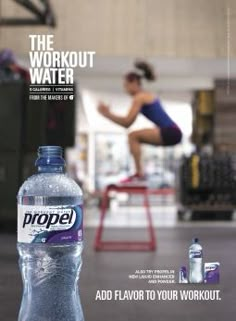 a bottle of propel water sitting on top of a table next to a woman