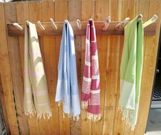 three towels hanging on a clothes line in front of a wooden wall