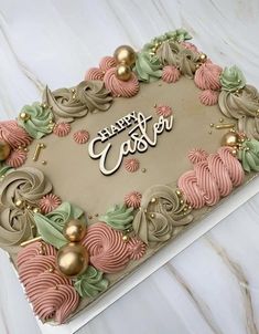 a birthday cake decorated with pink, green and gold icing on a white table