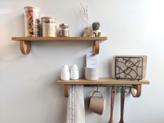 two wooden shelves with kitchen utensils and other items on them in a white room