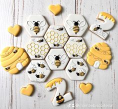 cookies decorated with honeybees and hearts are arranged on a white wooden table top