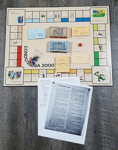 a board game is shown with pieces of paper and other items on the board, including an open book