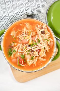 a bowl of chicken tortilla soup on top of a cutting board next to a green pot