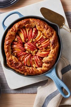 an apple pie in a cast iron skillet on a table with plates and utensils