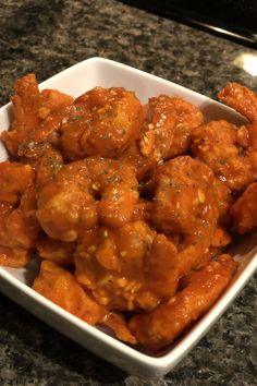 a white bowl filled with chicken wings covered in sauce