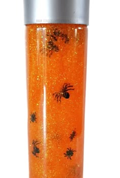 thermos cup is filled with orange glitter and black bugs on it's side