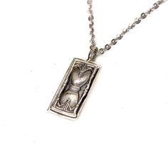 This pendant depicts an old world hourglass on the front, and a Cathedral Window on the reverse. This pendants was inspired by the hidden history, elements, and time of Tartaria. The hourglass is a powerful tool of symbolism, representing the passing of time, mortality, and the inevitability of change. It is a reminder that time is a precious resource and that it should not be wasted. The hourglass also symbolizes the cycle of life, with its sands representing the beginning and end of life. The cathedral window represents perfect geometry, as part of the larger cathedral architecture design.  They are usually made with stained glass, allowing the viewer to change their perspective on the world.  This pendant is made in white bronze, and oxidized for contrast. This item Ships For FREE Pleas Hourglass Necklace, Time Necklace, Beginning And End, Cathedral Window, Hidden History, Cathedral Windows, Cycle Of Life, Skull And Crossbones, Gold Style