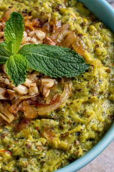 a blue bowl filled with food and garnished with green leaves