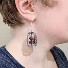 a close up of a person wearing some kind of earring with red stones in it