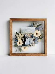 a wooden frame with flowers and photos in it