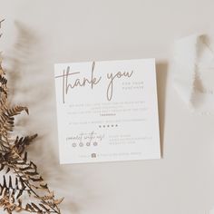 a thank you card sitting on top of a table next to a plant and tissue paper