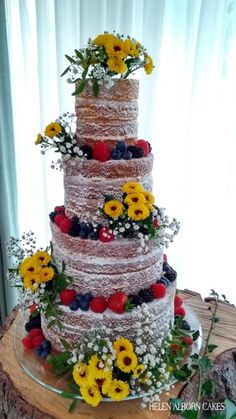 a multi tiered cake with fresh fruit and flowers