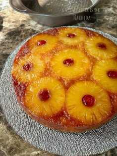 a pineapple upside down cake sitting on top of a metal plate next to a pan