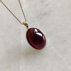 ITEM DESCRIPTION: >> The Pendant is made from Solid 14K Yellow Gold. Gemstone used is absolutely natural and ethically sourced. >> Natural Garnet in cabochon cut and oval shape with bezel setting is studded on it with utmost precision. >> This is a minimalist design and is absolutely hassle-free and everyday jewelry. Gem: Garnet Gem size: 14x19 mm oval Gem weight: 20.66 carats Gold purity: 14K (58.33% approx.) Gold weight: 0.62 grams Gross weight: 4.75 grams The Gold purity is guaranteed and it Garnet Pendant Necklace, Garnet Necklace Vintage, Heirloom Garnet Jewelry For Gifts, Gold Garnet Jewelry With Bezel Setting, Formal Garnet Jewelry With Bezel Setting, Elegant Gold Cabochon Gemstones, 14k Gold Gemstones With Bezel Setting For Gift, Yellow Gold Oval Cabochon Jewelry Gift, Gift Oval Cabochon Necklace With Polished Finish