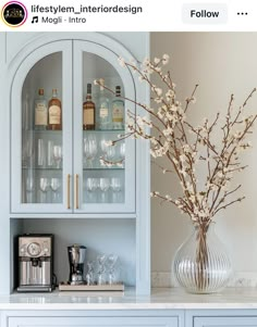 a vase filled with flowers sitting on top of a counter next to a glass cabinet