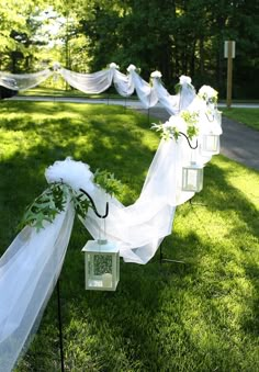 a row of white flowers and lanterns on the grass