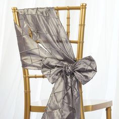 the back of a chair with a bow tied to it's seat and gold frame