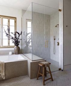 a bathroom with a tub, shower and stool next to the bathtub is shown