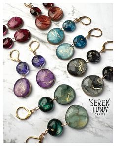 a bunch of different colored glass beads hanging from gold hooks on a white marble surface