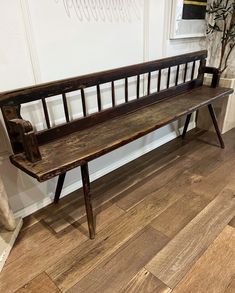 a wooden bench sitting on top of a hard wood floor next to a white wall