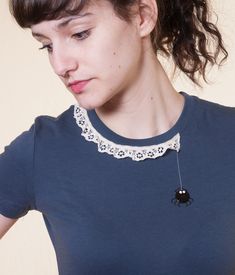 a woman wearing a necklace with a black and white spider charm on it's neck