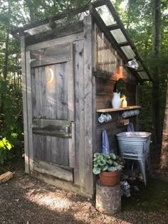 an outhouse in the woods with potted plants and other things on it's shelf